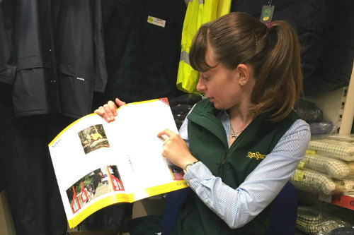 Young woman with hair in pony tale pointing to text in brochure.
